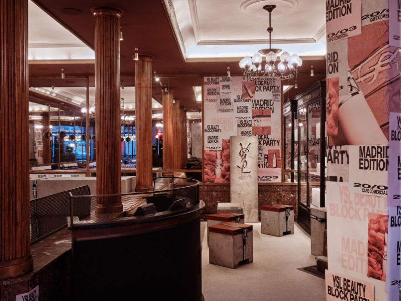 Café Comercial area with YSL panel, historic columns, and event graphics across walls and structures